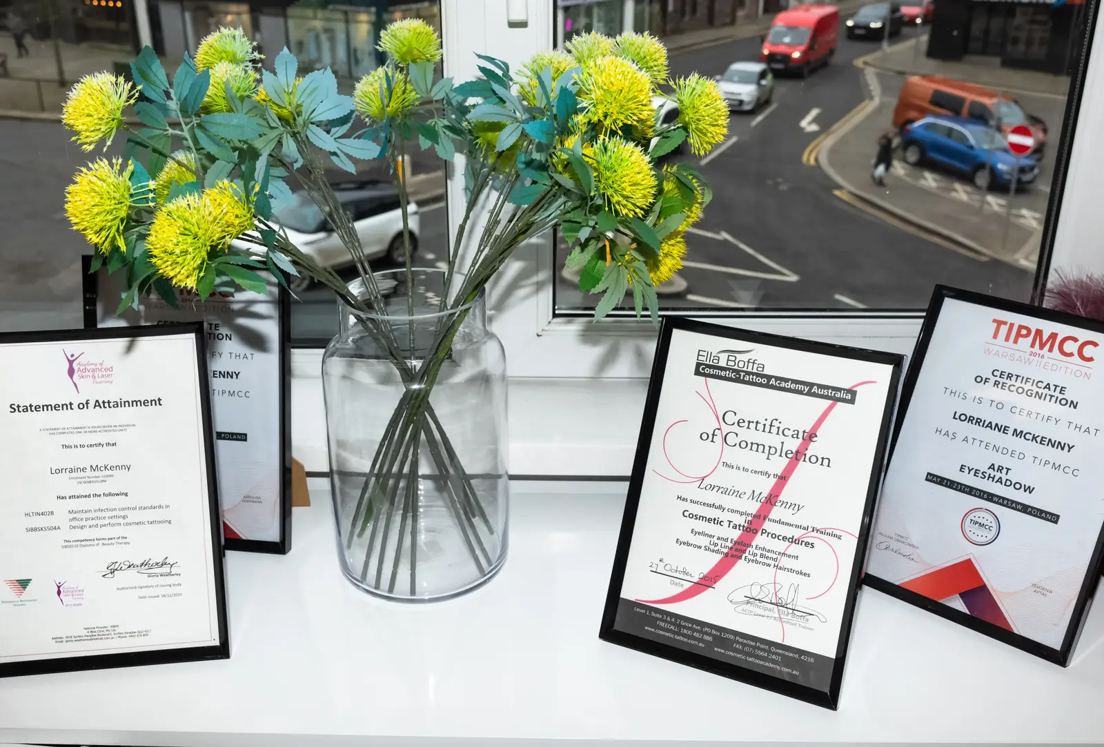 A selection of Lorraine Nugent's cosmetic tattoo training certifications from Australia, Northern Ireland and Poland displayed at the clinic