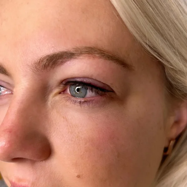 Subtle eyeliner tattoo on blonde — natural definition for blue eyes without makeup