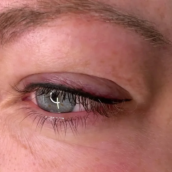 Winged eyeliner tattoo on mature skin — soft cat-eye definition
